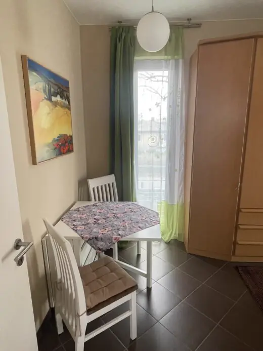 Schlafzimmer mit Tisch, Stühlen und Kleiderschrank am Fenster