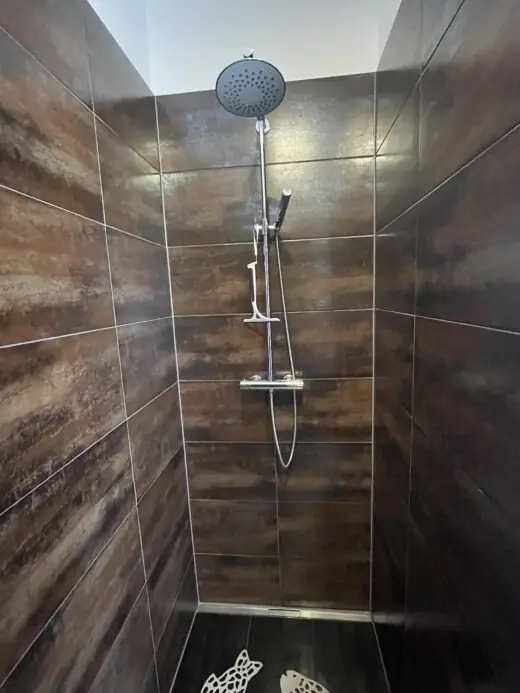 Dusche mit Regendusche und dunklen Fliesen