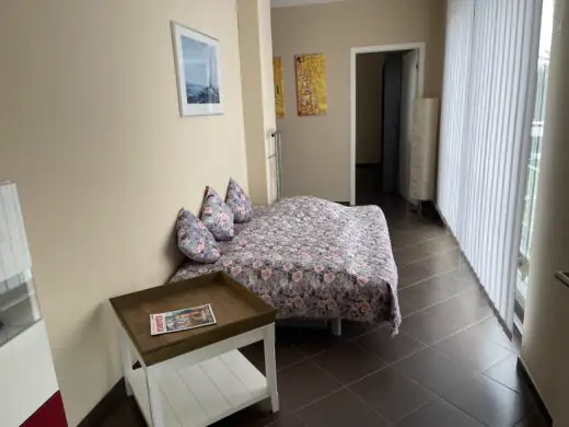 Durchgangszimmer mit Doppelbett und Beistelltisch, Blick zur Tür