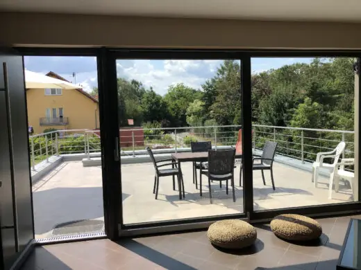 Blick durch die Glasfront auf die Terrasse mit Sitzgruppe, im Vordergrund Sitzkissen